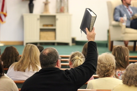 A member of the congregation holding a Bible during worship